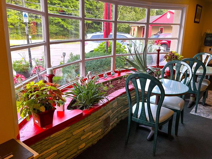 A room with tables and chairs in front of a large window.