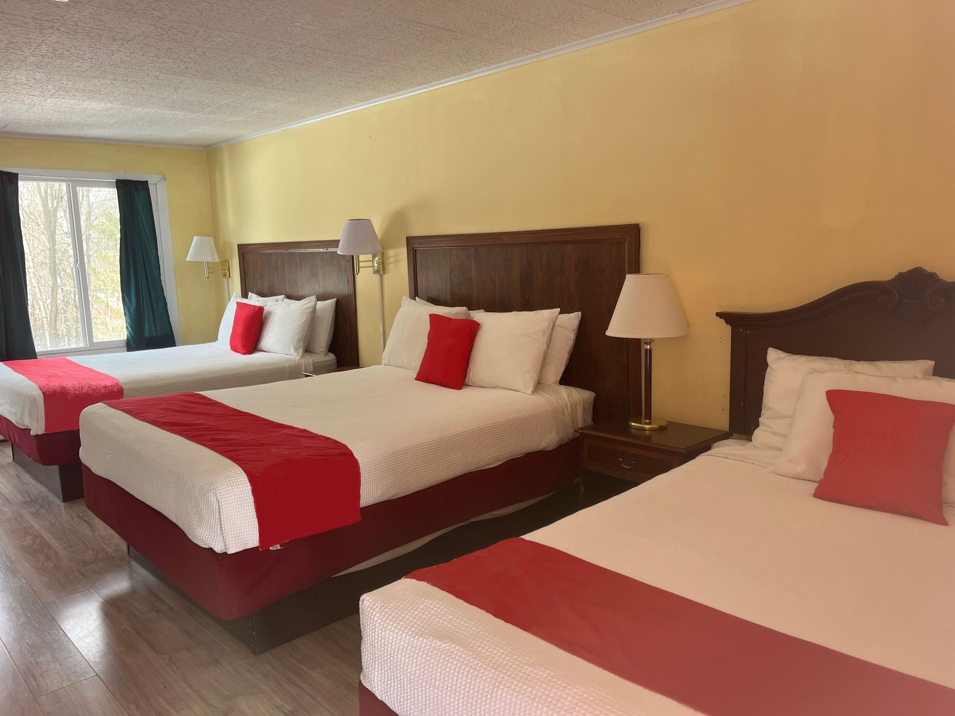 A hotel room with three beds and a window