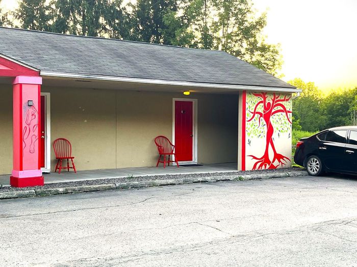 A car is parked in front of a building with a red door