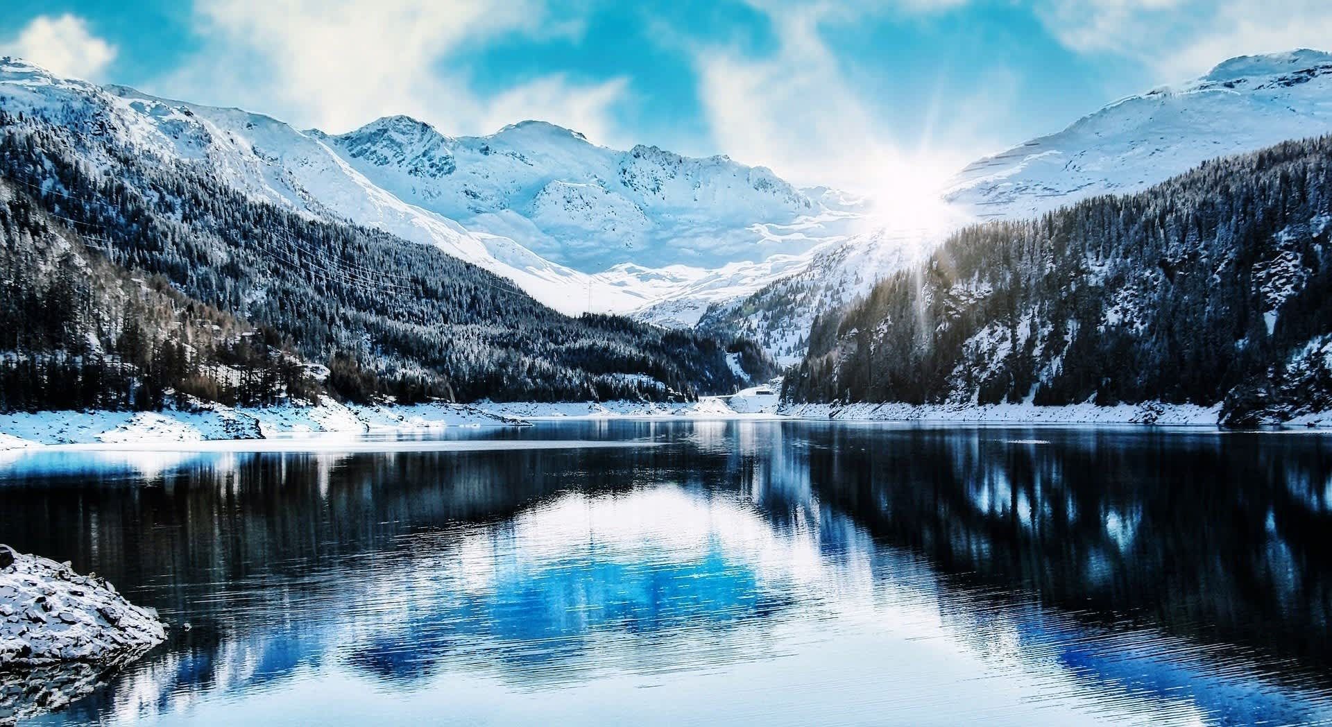 A lake surrounded by snow covered mountains and trees