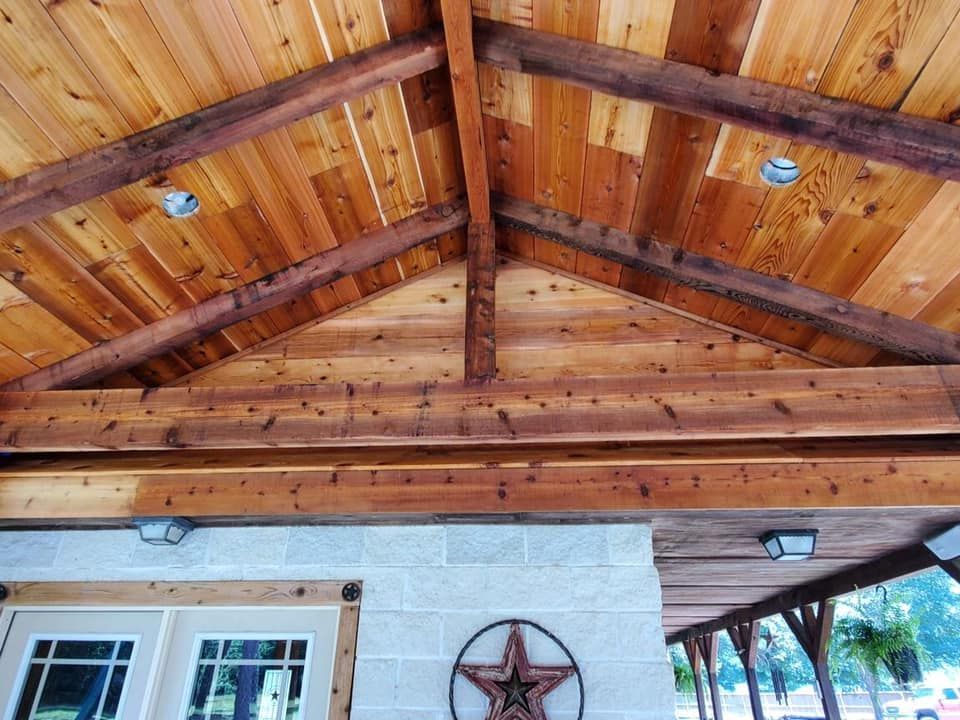 Wooden ceiling with beams, recessed lights, over a stone and wood structure.