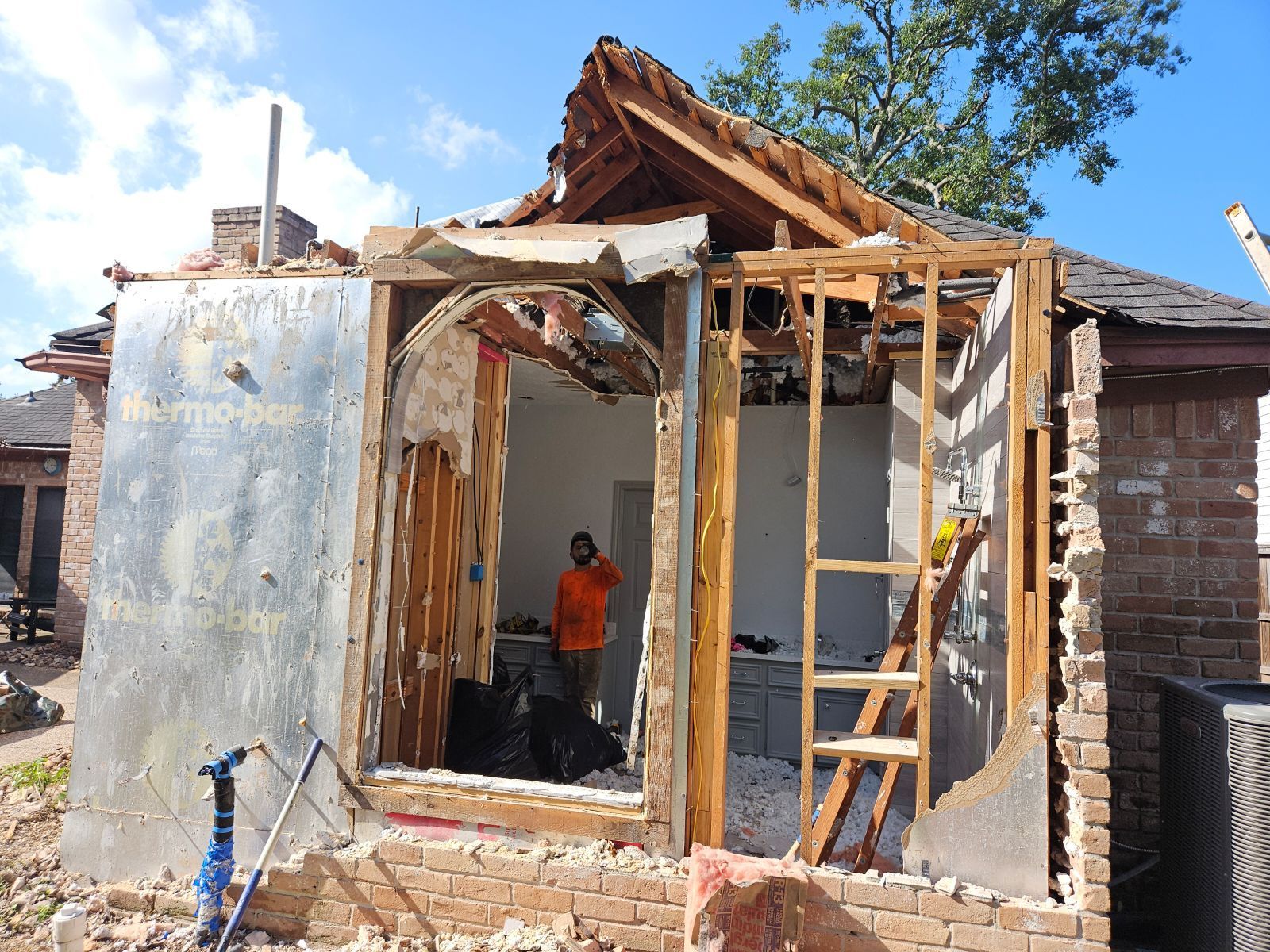 Partial demolition of a brick building; a worker stands inside.