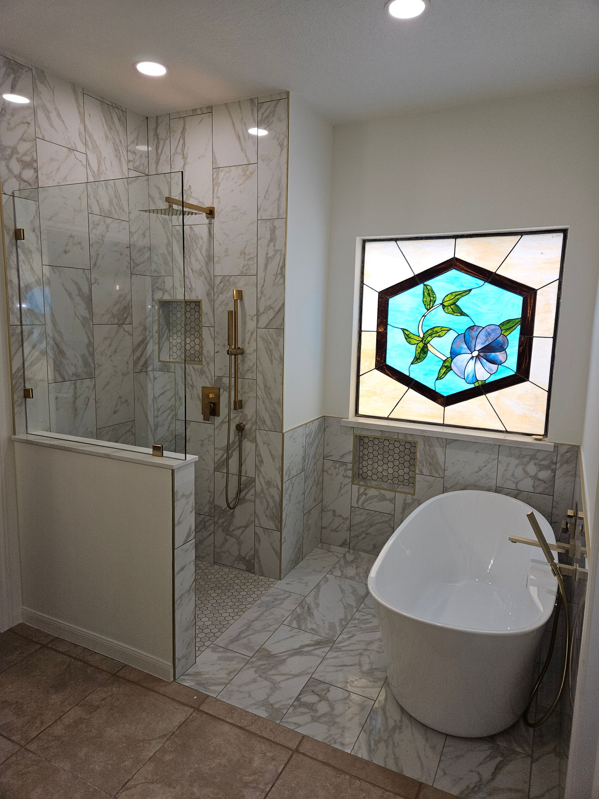 Bathroom with marble shower and floor, a white freestanding tub, and stained glass window.