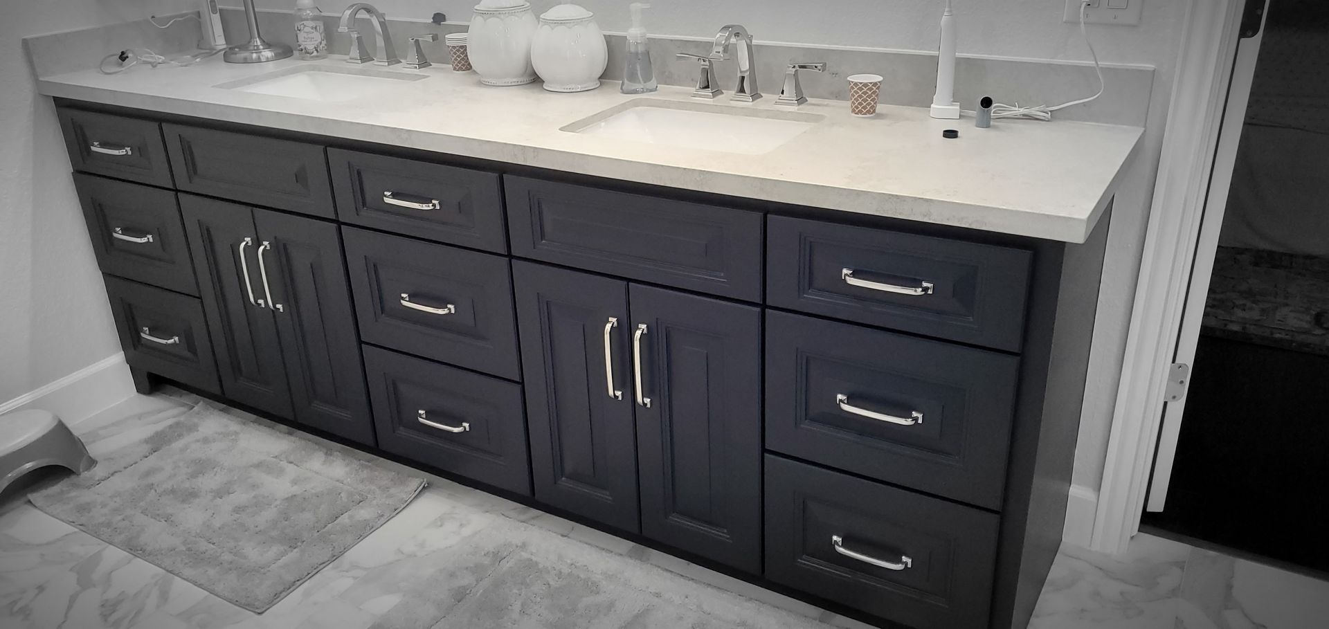 Dark blue bathroom vanity with silver handles and white countertop.
