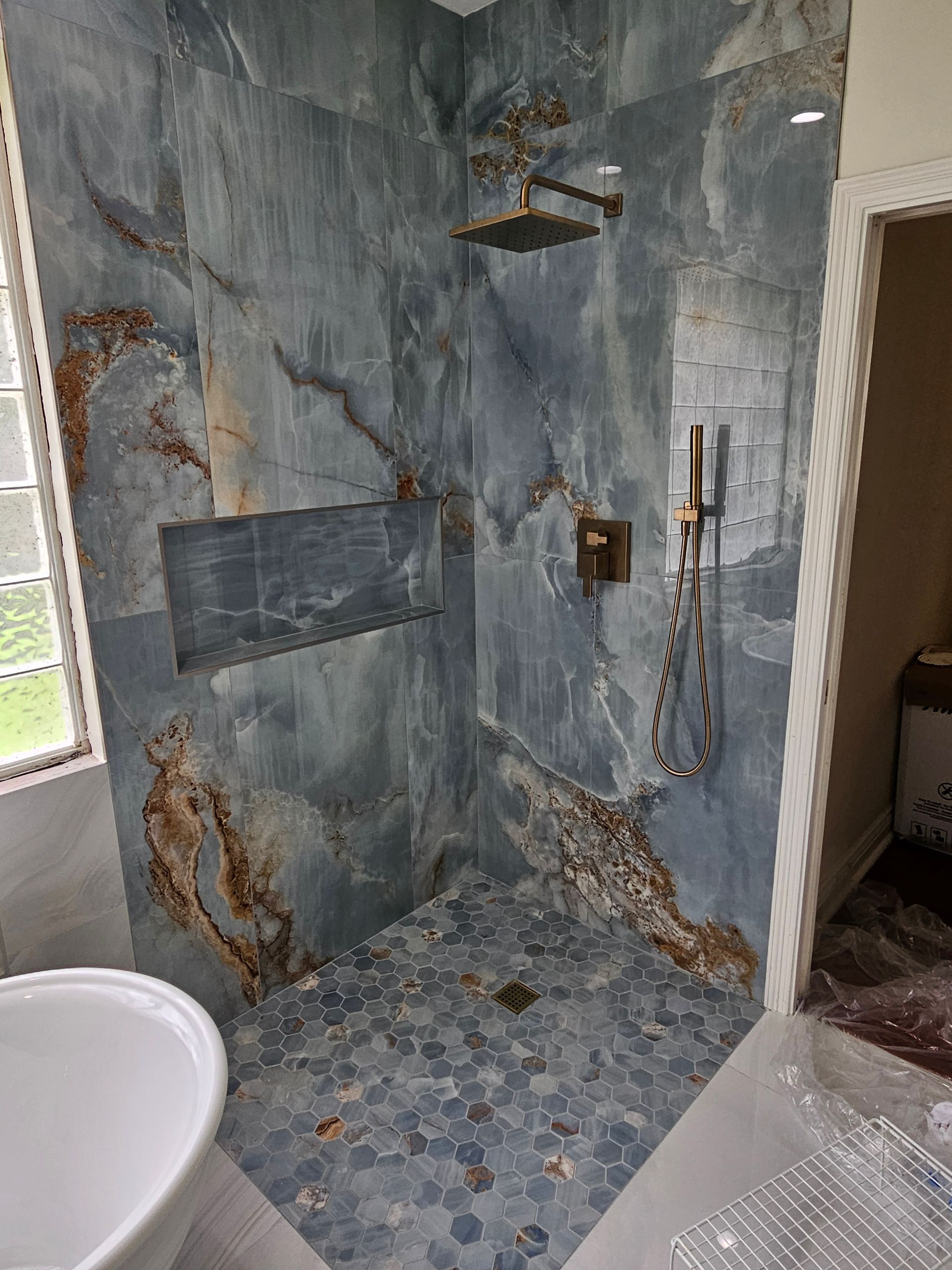 Blue and rust-colored tile shower with gold fixtures.