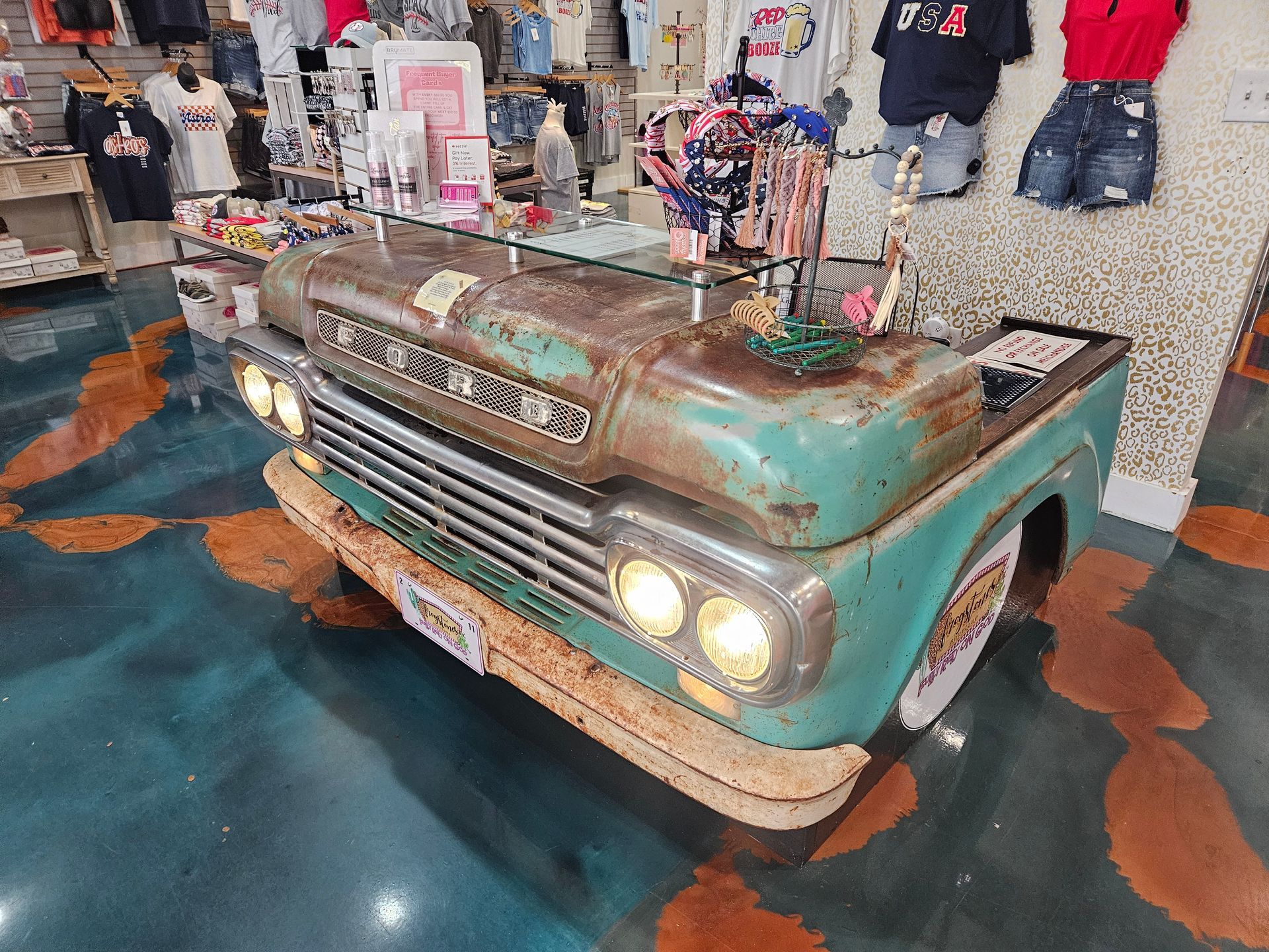 Desk made from the front of a rusty teal Ford pickup truck in a clothing store.