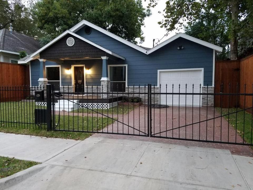 Blue house with a white garage and black iron fence.