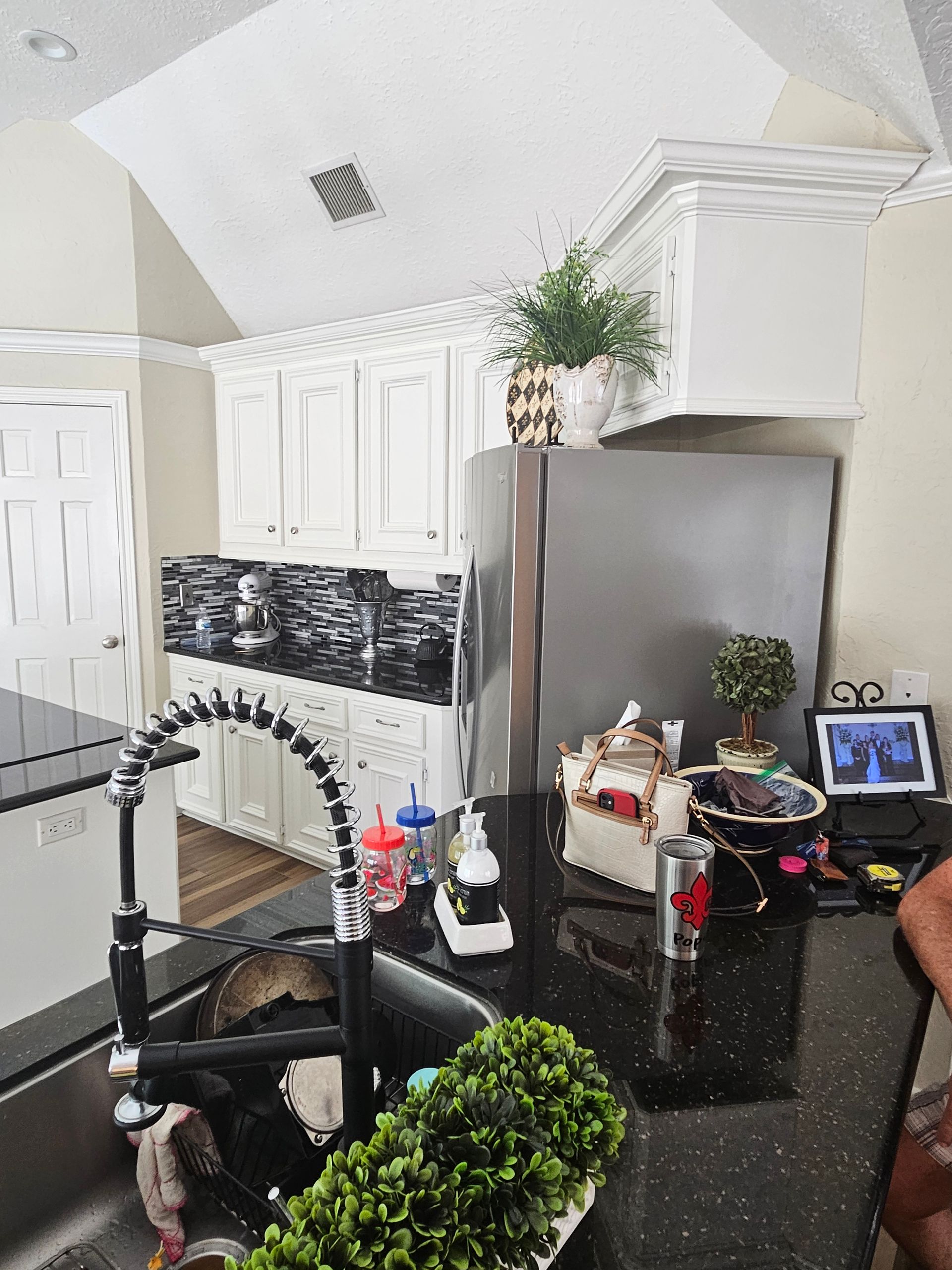 Kitchen with black granite countertops, stainless steel appliances, and white cabinets.