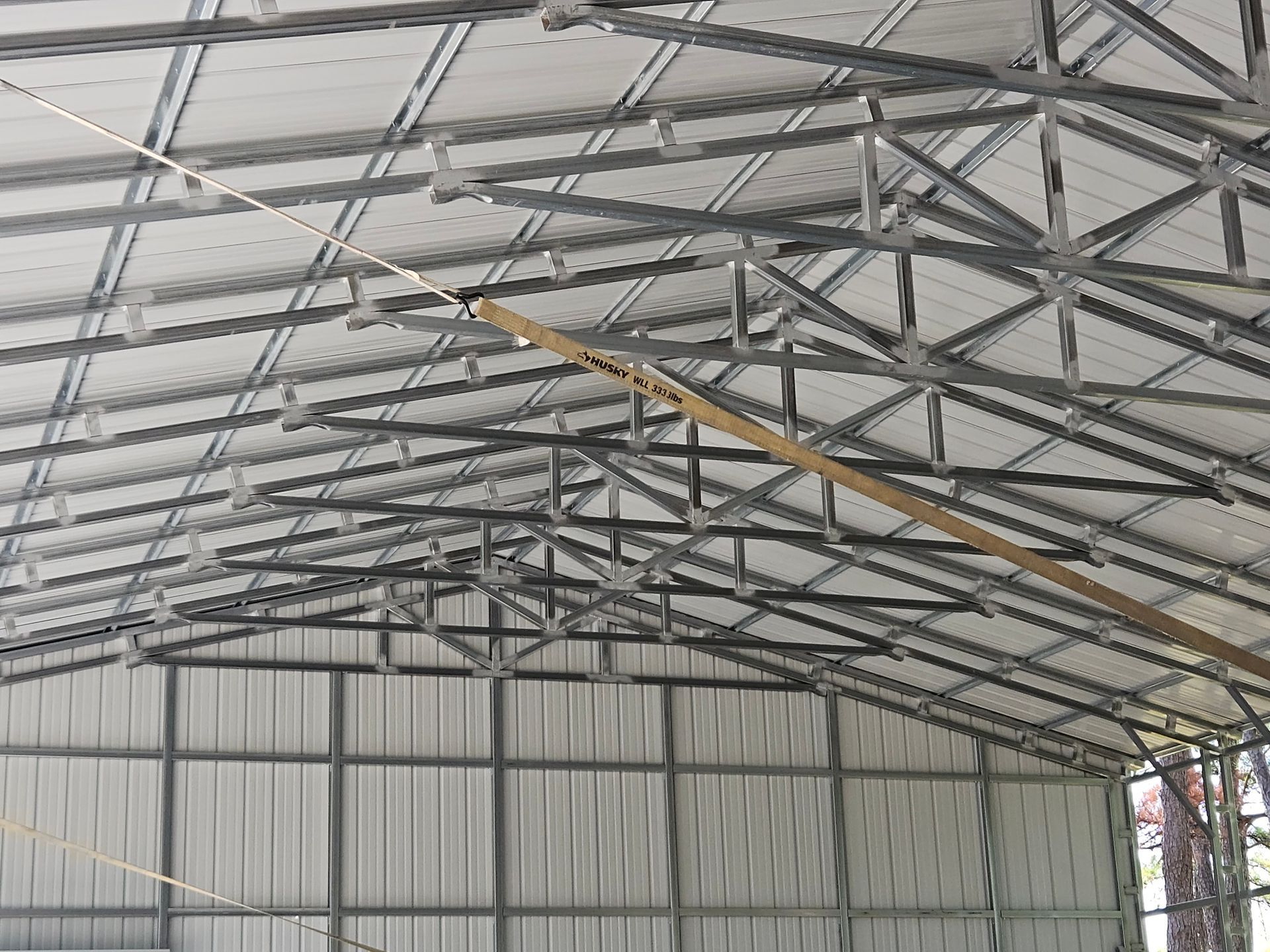 Interior view of a metal roof structure; gray metal beams and corrugated metal siding.
