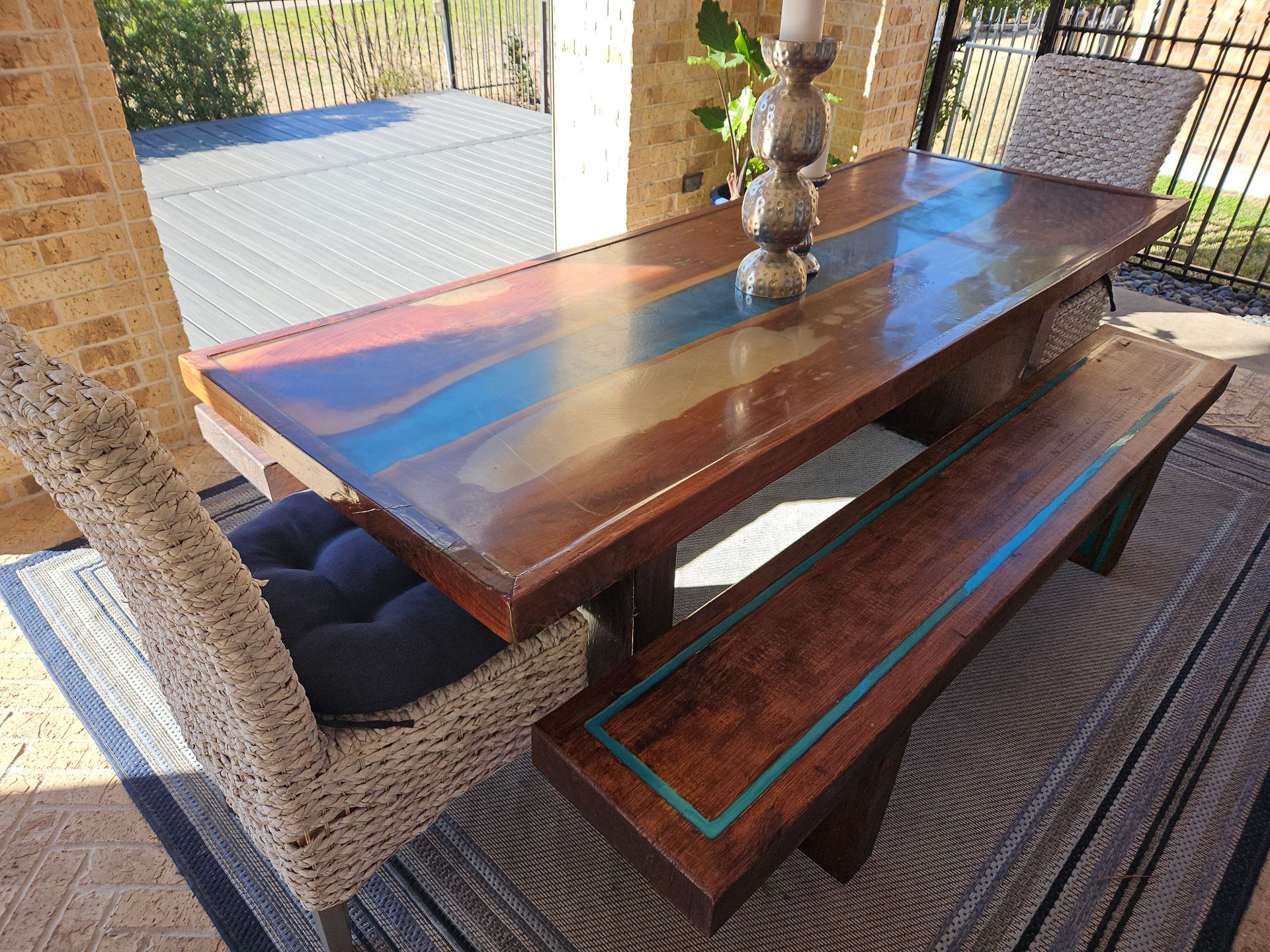 Outdoor wooden table and bench set with a woven chair.