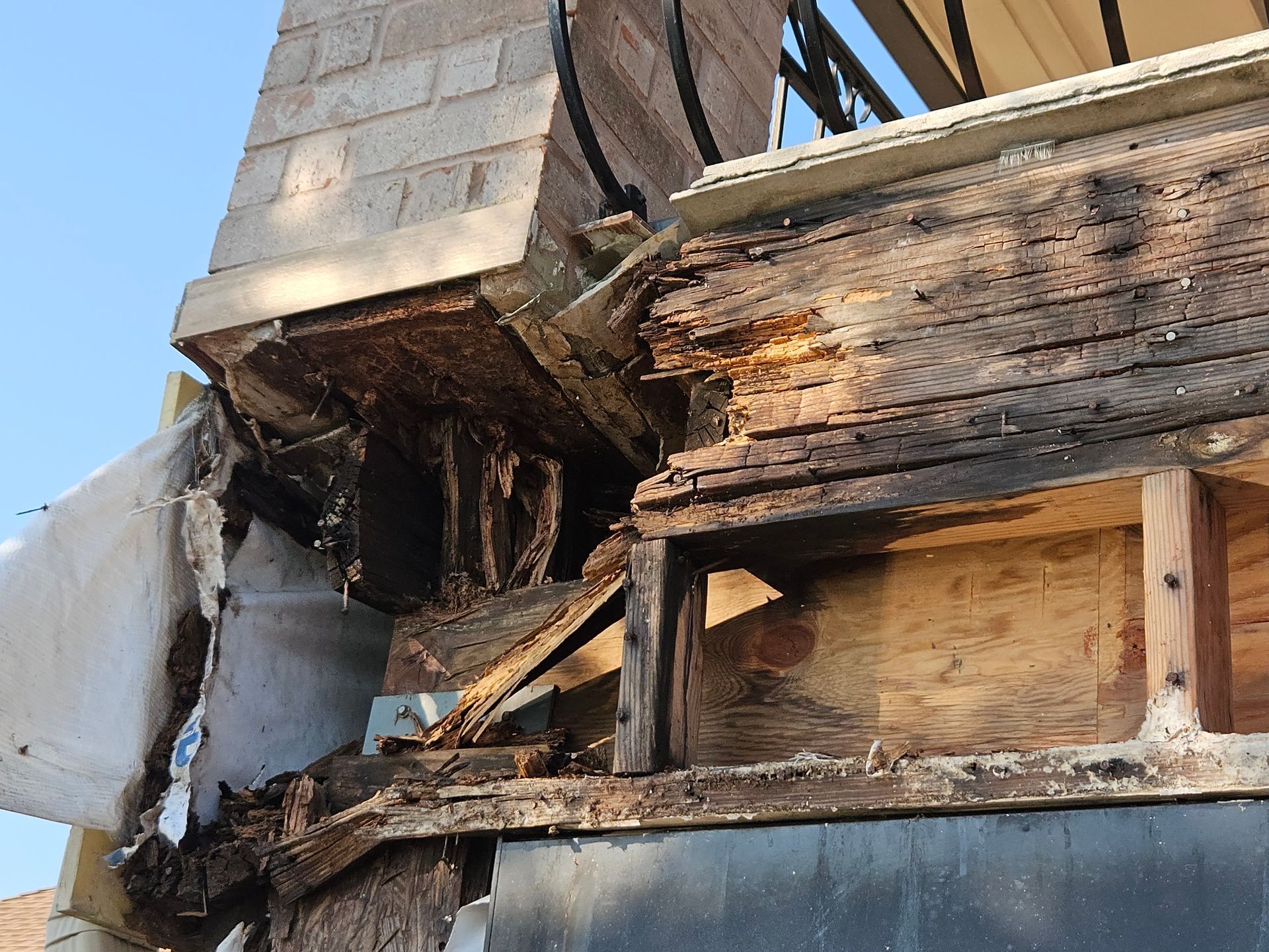 Damaged exterior of a building, showing severely rotted wood near a chimney.