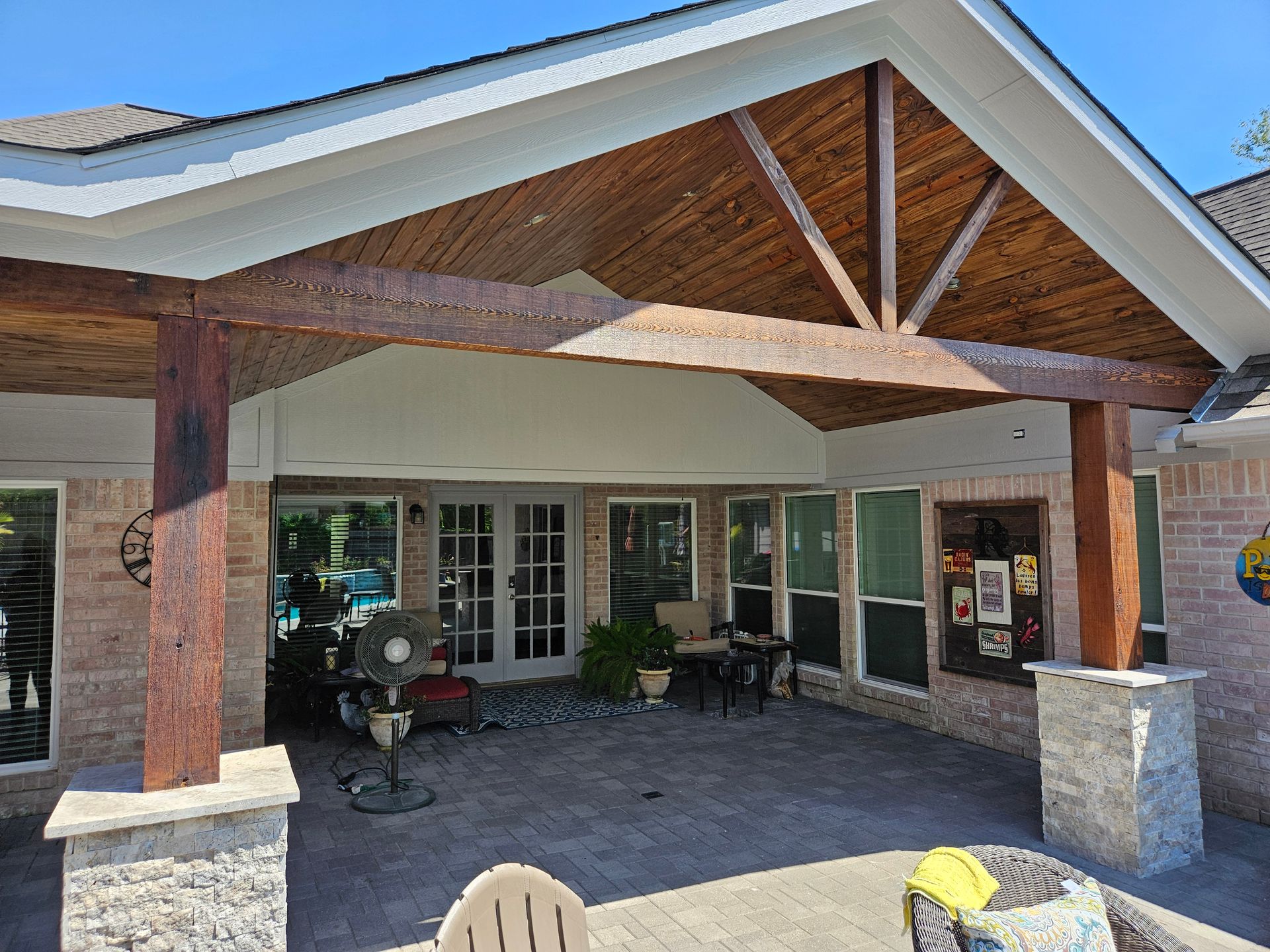 Outdoor patio with brick columns, wooden beams, and a stone patio.