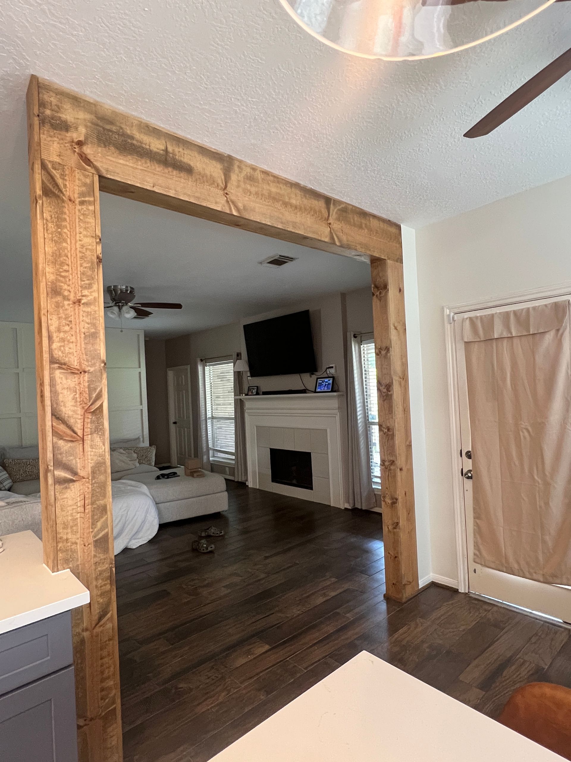 Rustic wood doorway framing a view of a living room with fireplace, TV, and dark wood floors.