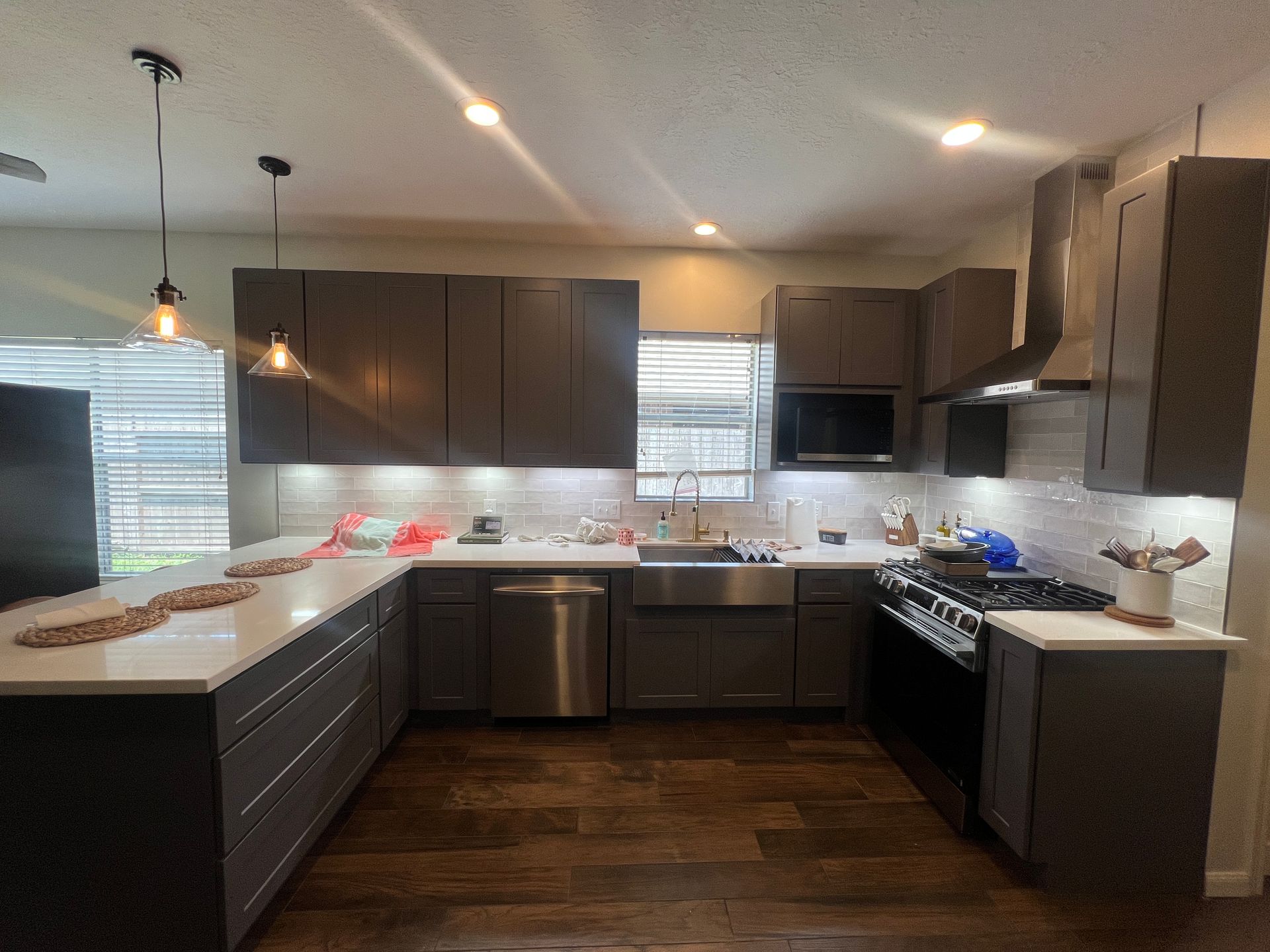 U-shaped kitchen with gray cabinets, white countertops, stainless steel appliances, and hardwood floors.