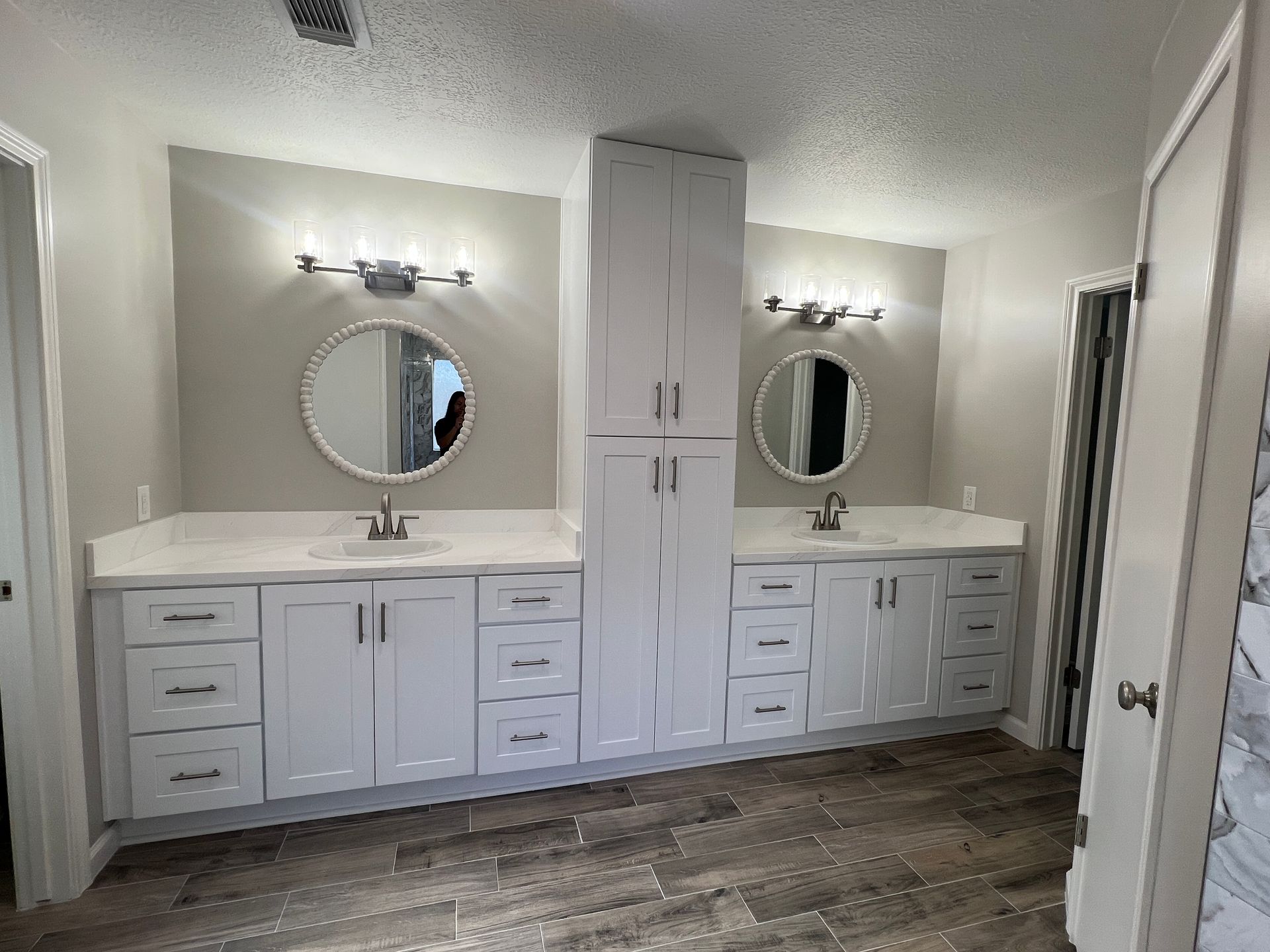 White double sink bathroom vanity with neutral walls and wood-look flooring.