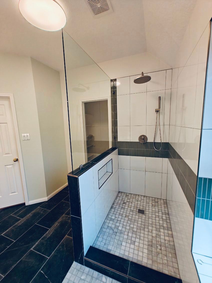 Modern shower with glass partition and white, blue, and black tile.
