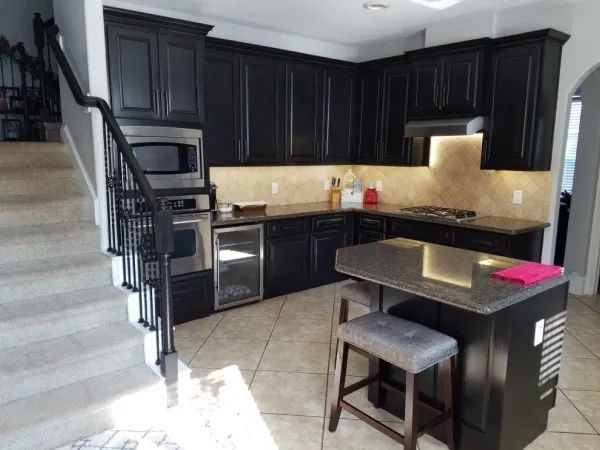 Black kitchen cabinets with granite countertops and a breakfast bar. Includes a staircase.