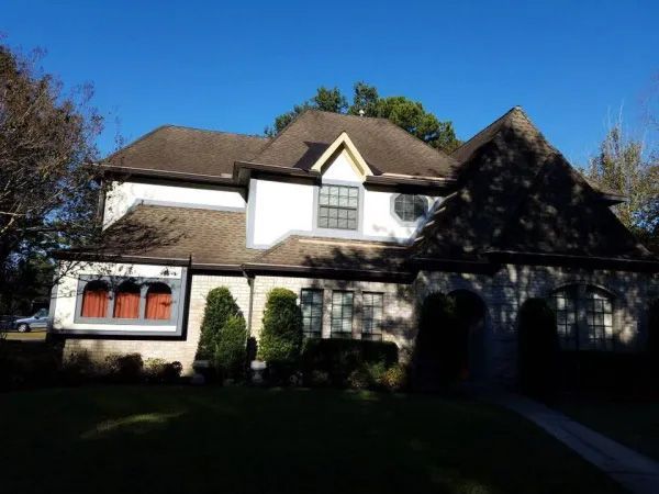 Two-story house with white and stone exterior under a blue sky.