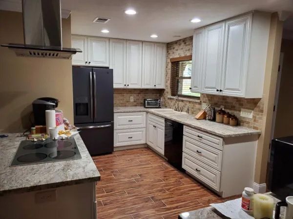 Kitchen with white cabinets, granite counters, and stainless steel appliances; wood-look flooring.
