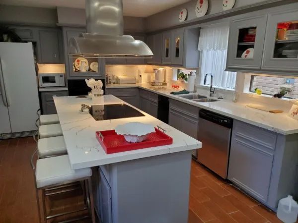 Gray kitchen with island seating, stainless steel appliances, and white countertops.