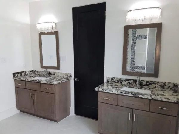 Bathroom with two vanities, dark door, and crystal light fixtures.