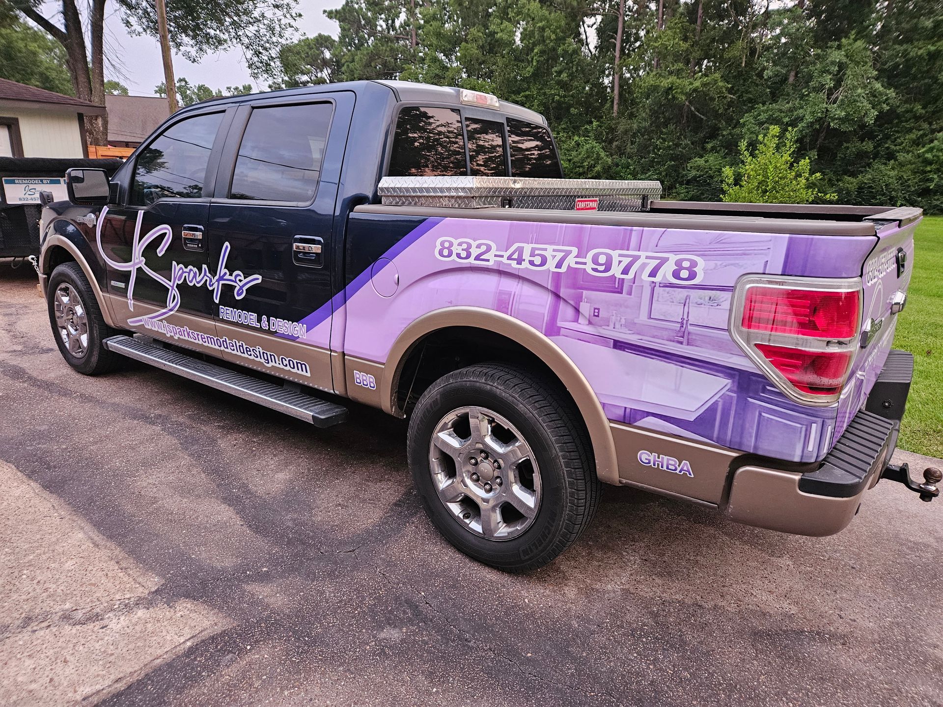 Ford pickup truck with purple and gold wrap, business logo, parked on a driveway.
