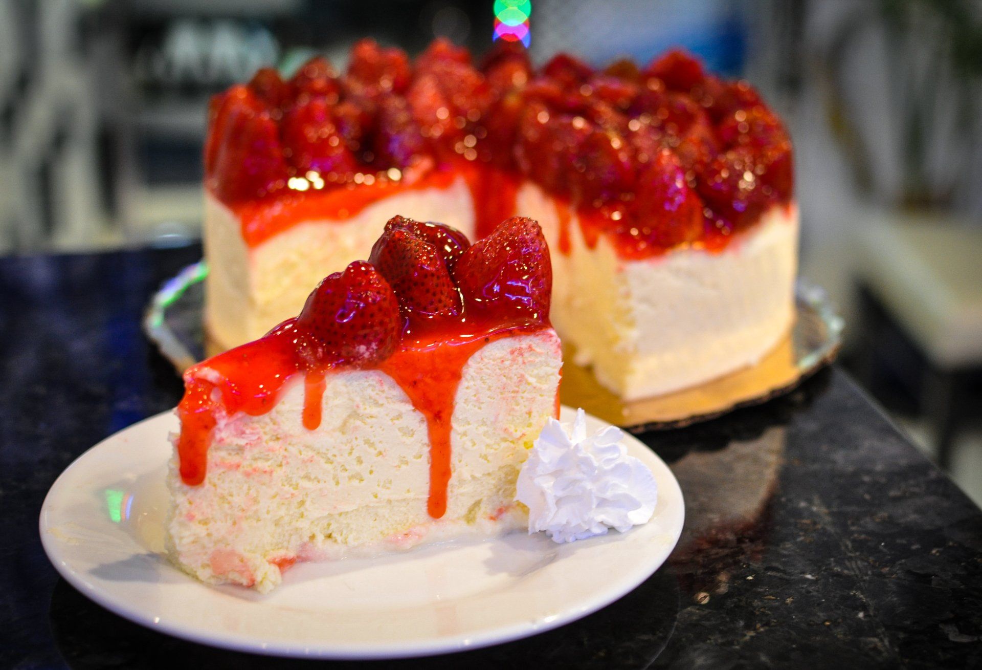 A slice of cheesecake with strawberries on top is on a white plate.