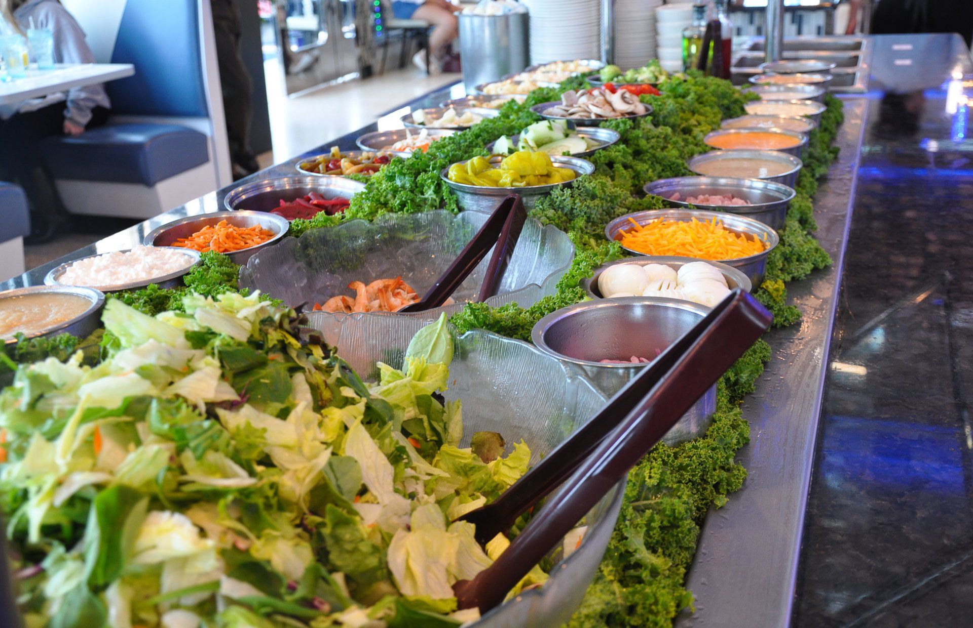 A salad bar with lots of vegetables and condiments