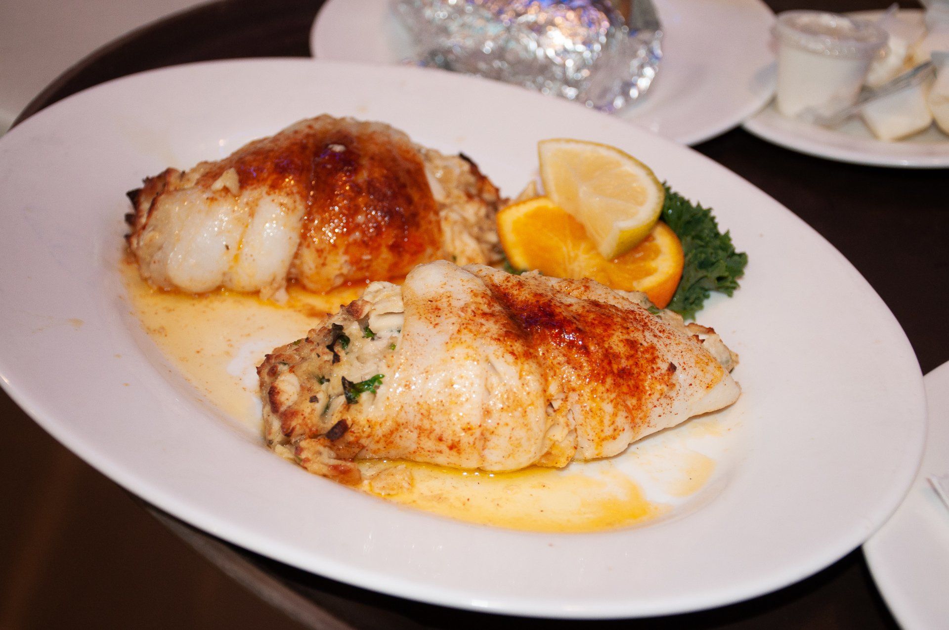 A white plate topped with two pieces of fish and lemon slices.