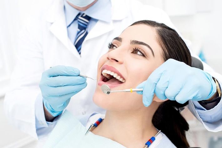 A dentist inspecting dentures in a woman's mouth