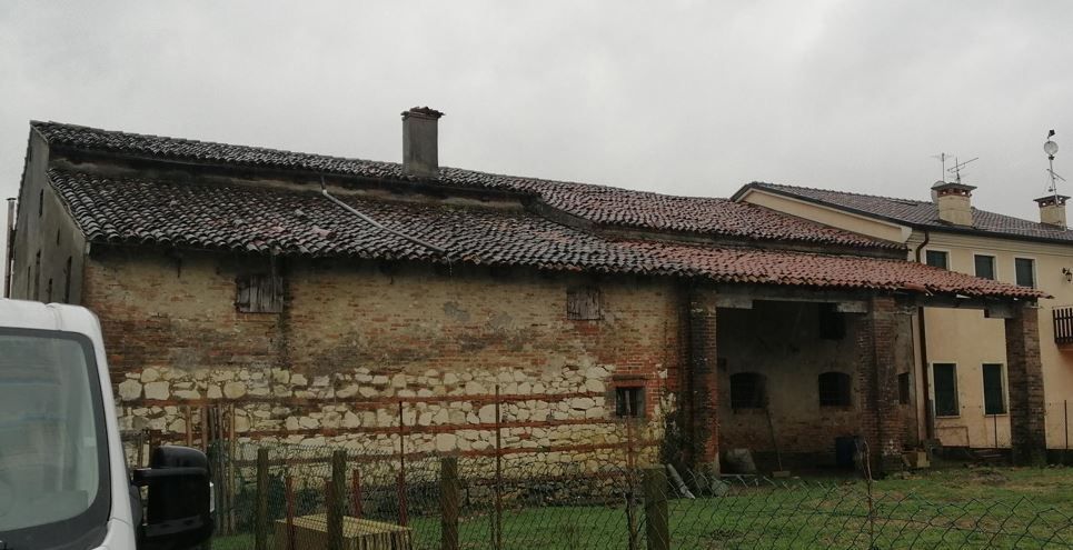 Un furgone bianco è parcheggiato davanti a un edificio in mattoni con il tetto di tegole.