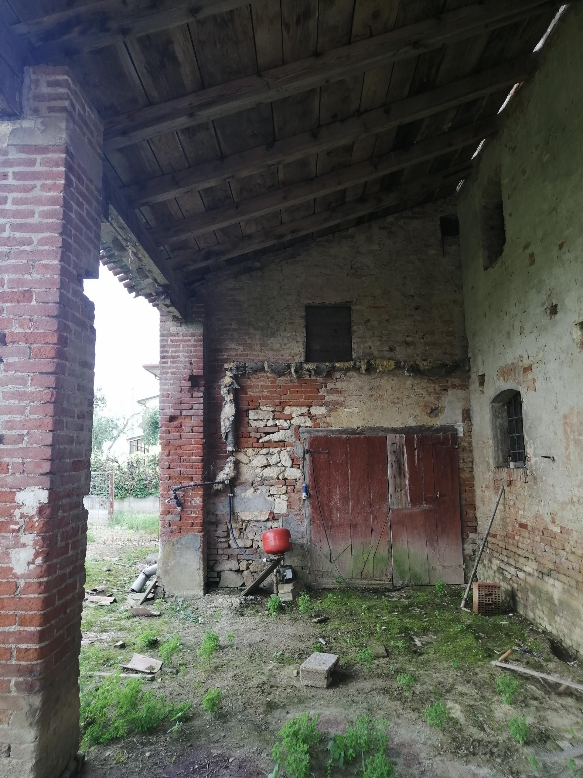 Un edificio in mattoni con un tetto in legno e una porta rossa
