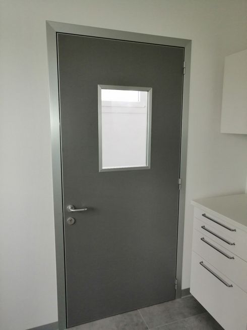 Una porta grigia con una piccola finestra al suo interno