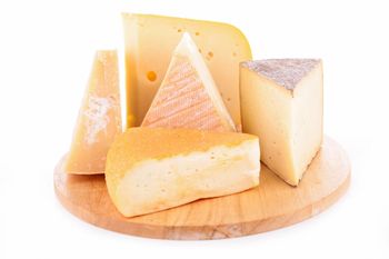 Una tabla de cortar de madera cubierta con diferentes tipos de queso.