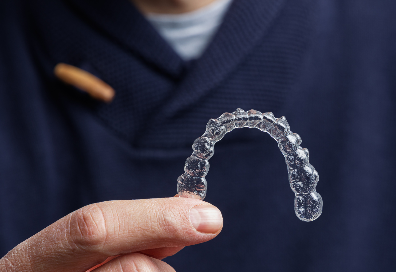 A person is holding a clear brace in their hand.