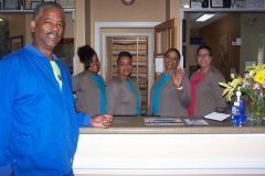 A man in a blue jacket is standing in front of a dental office reception desk.