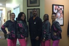 A group of dental assistants are posing for a picture in a hallway.