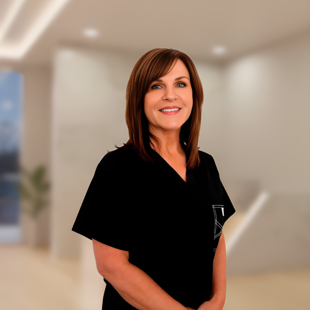 Smiling healthcare worker in black scrubs standing in a bright hospital hallway