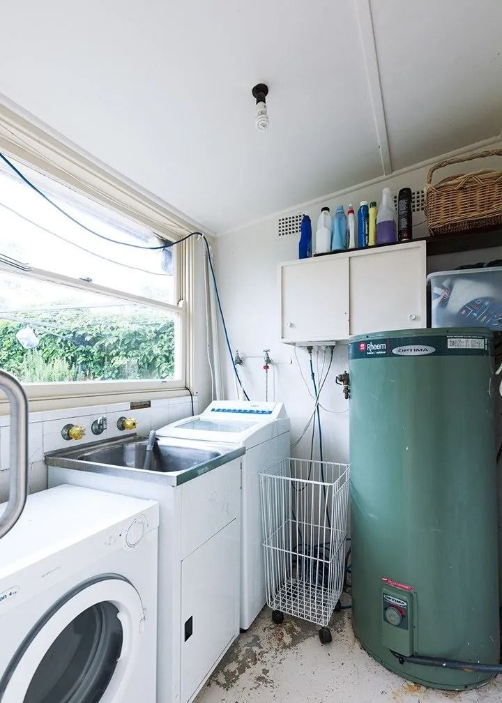 A Laundry Room with A Washer and Dryer and A Green Water Heater — Aqua Blue Plumbing Services in Coffs Harbour, NSW 