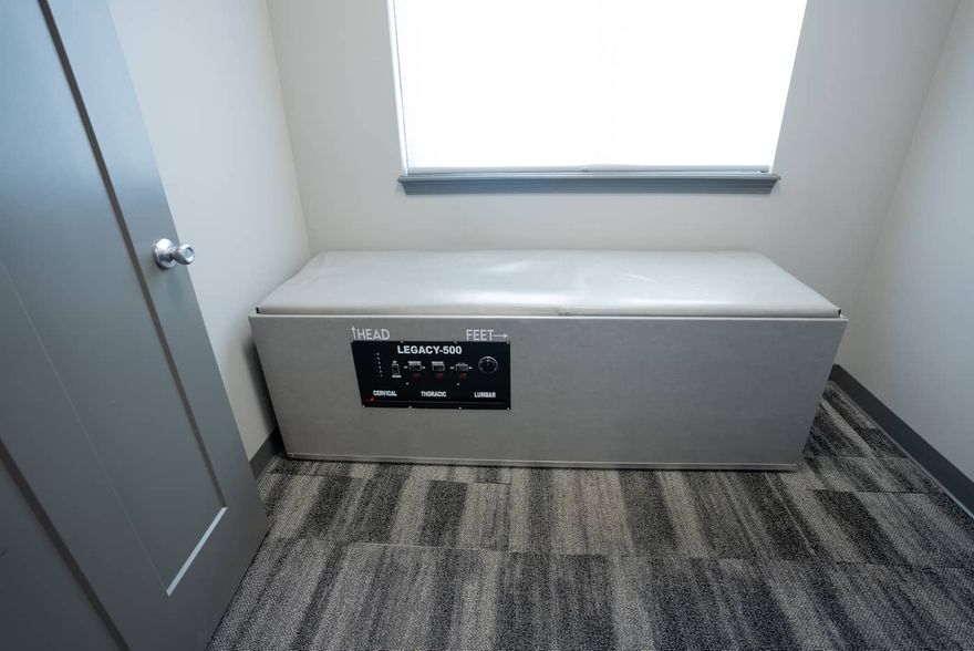 A gray ottoman is sitting in a room next to a window.