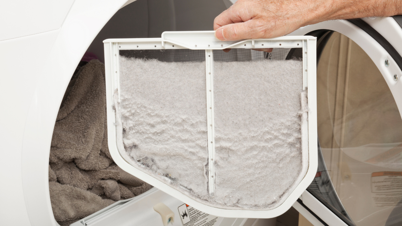 A person is cleaning a lint filter in a dryer.