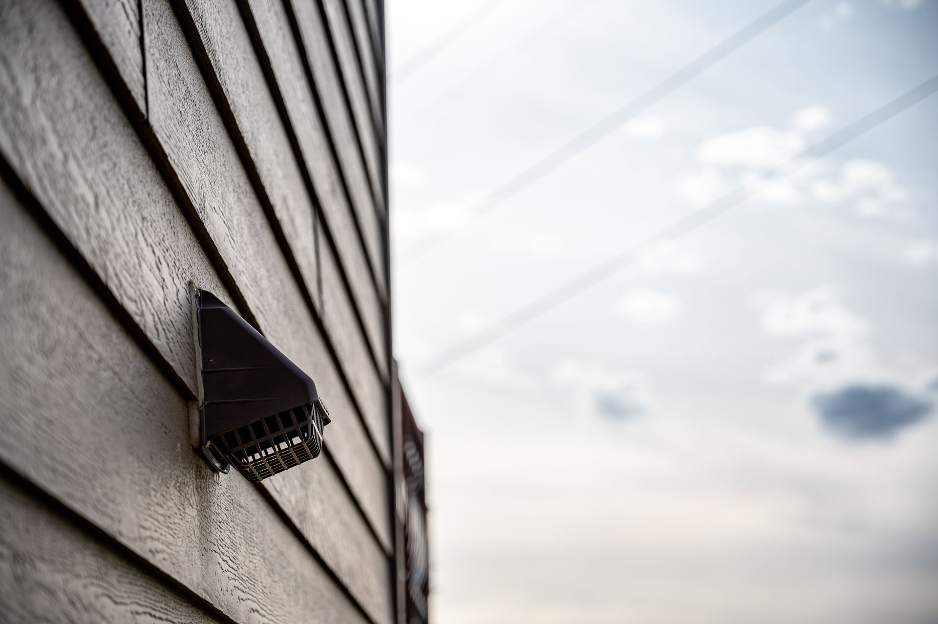 Dark brown house siding with a dryer vent vent.