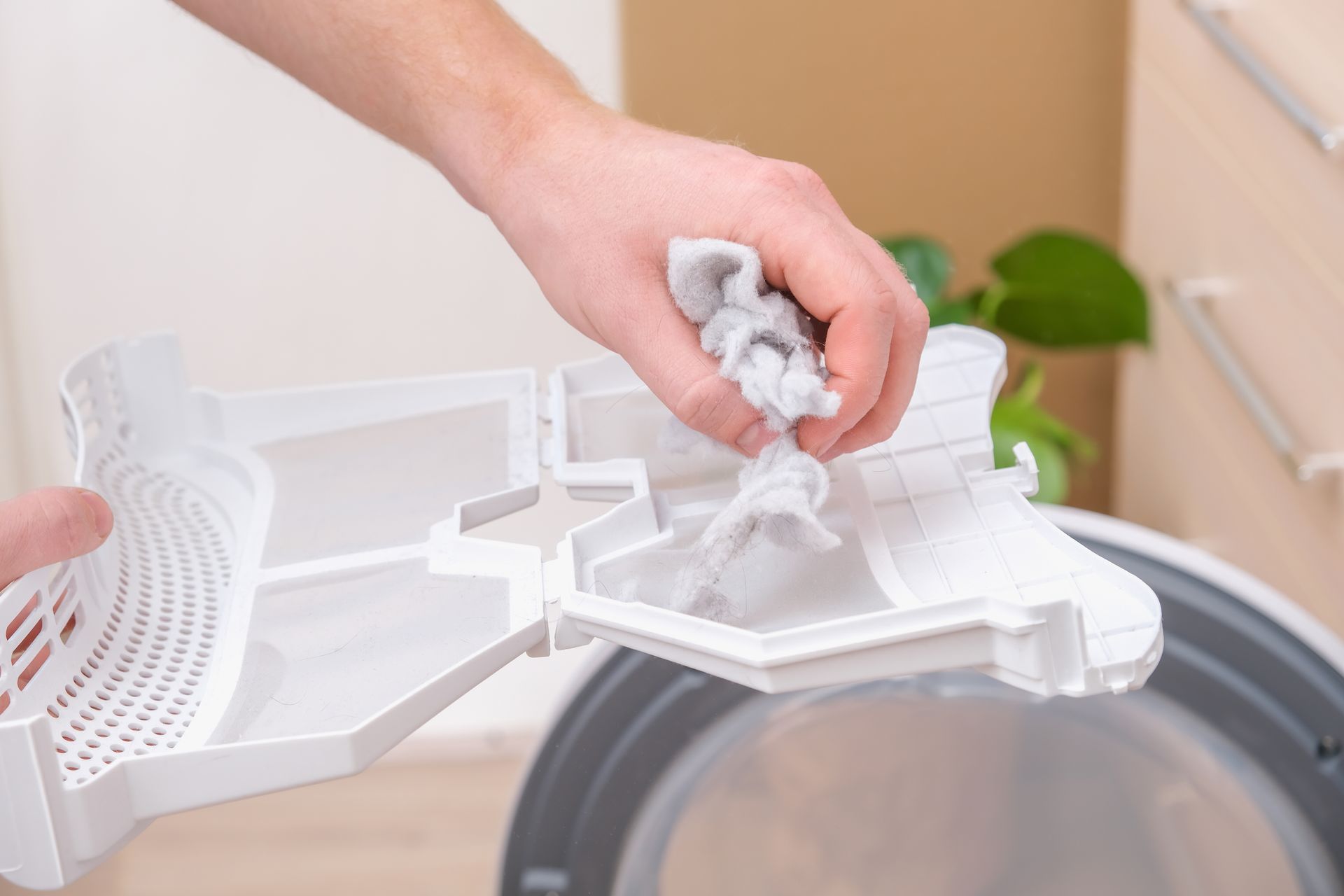 A person is cleaning a dryer filter with a cloth.