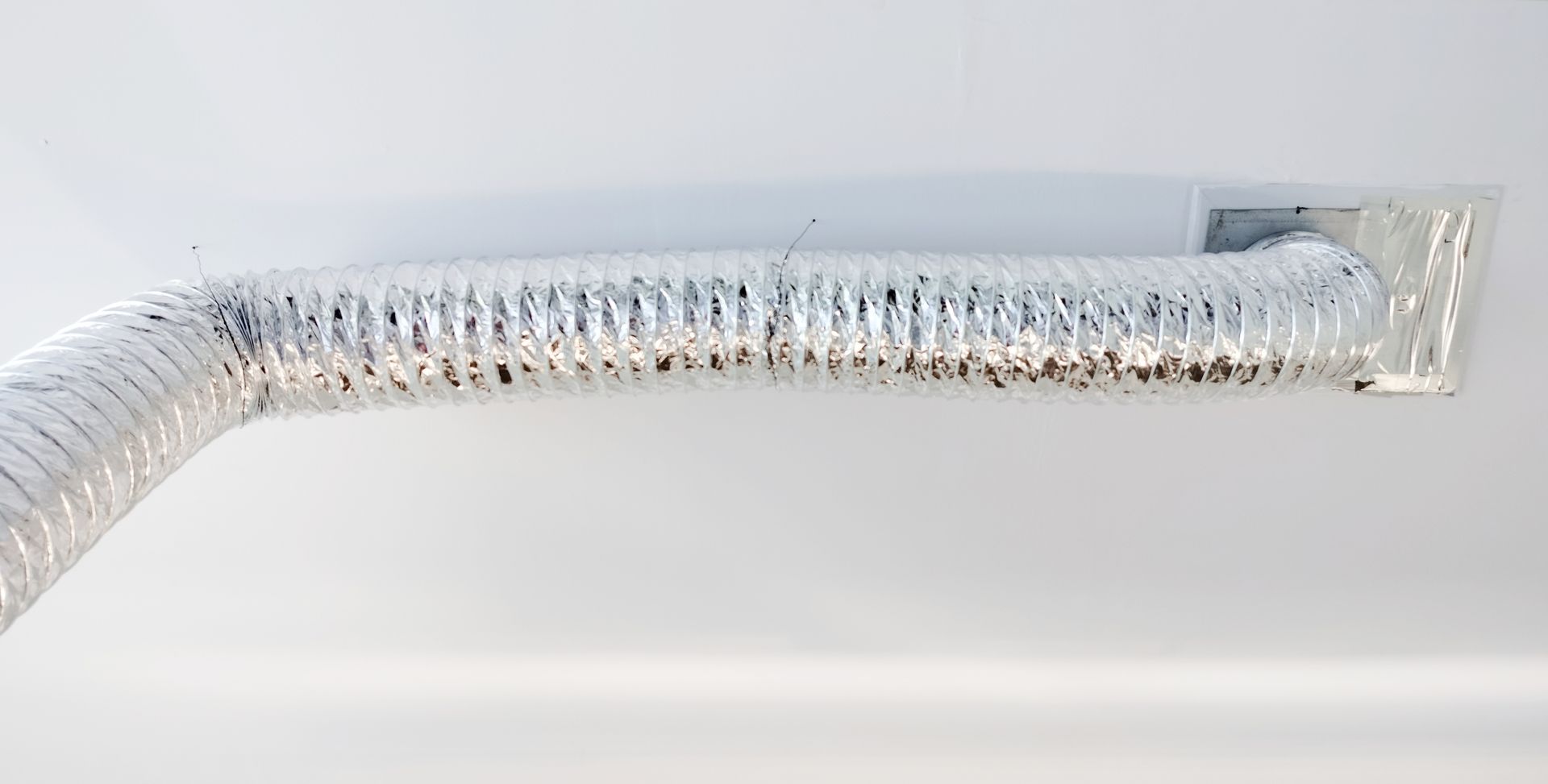 A close up of a duct on a white wall.