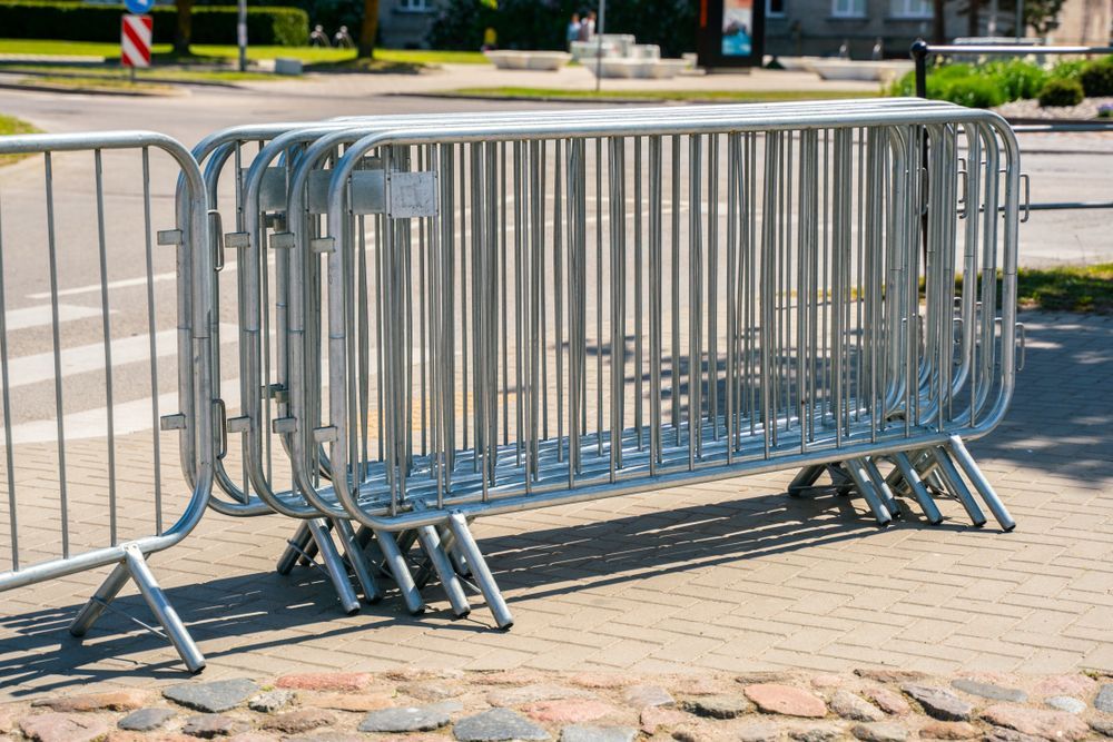 Hand painting a wooden fence with brown stain against a blue sky.