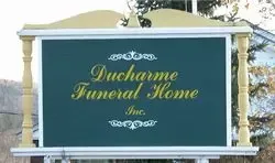Sign for Ducharme Funeral Home, Inc., featuring a dark green background with gold lettering.