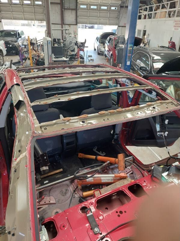 A red car with the roof removed in a garage