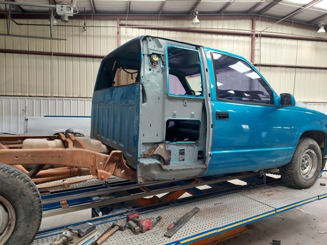 A blue truck is sitting on a lift in a garage