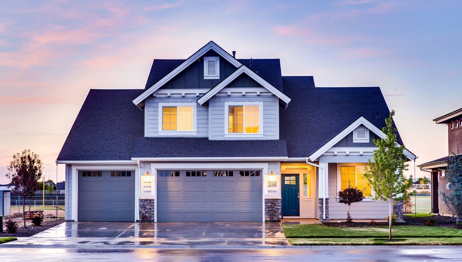 A large house with a blue roof and a blue door is lit up at night