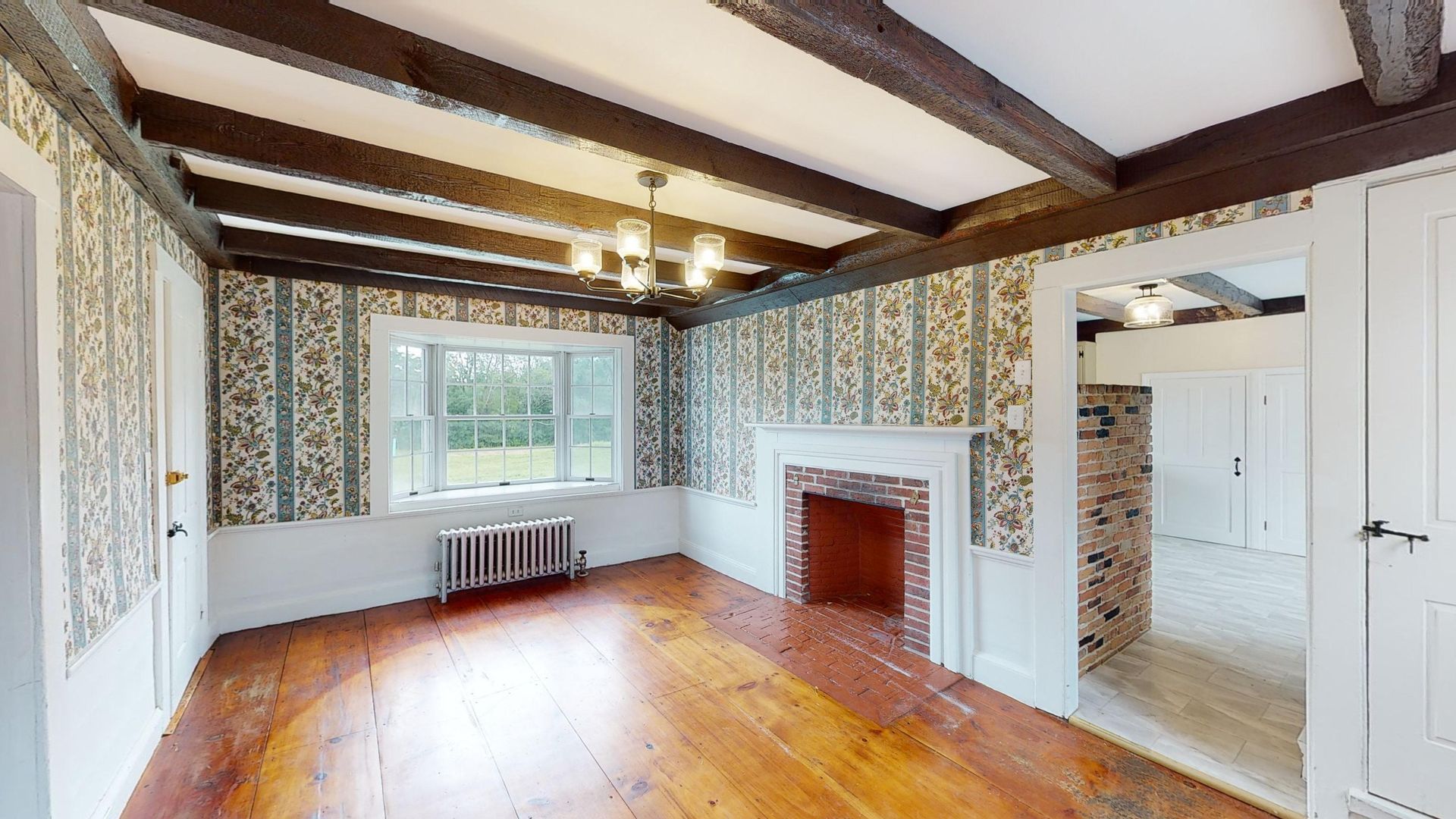 An empty living room with a fireplace and a large window.